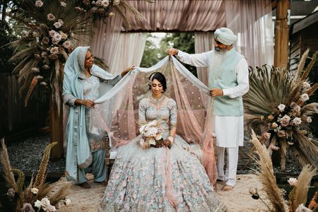 Bride getting ready with her parents draping the dupatta over her