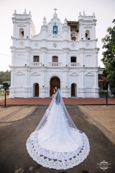 A Christian bride poses in a white wedding gown with a long train