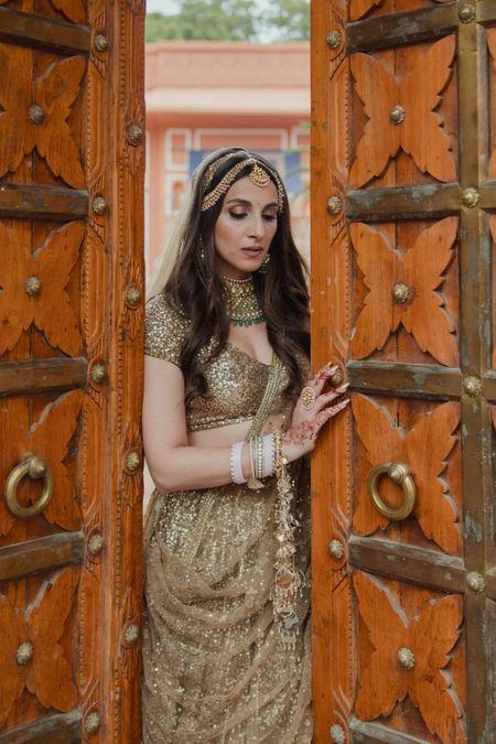 Photo of Classic bridal portrait with bride in a all-gold lehenga with shimmer details