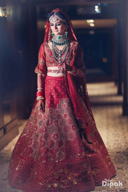 Photo of Bride in red with contrasting layered jewellery and waist belt
