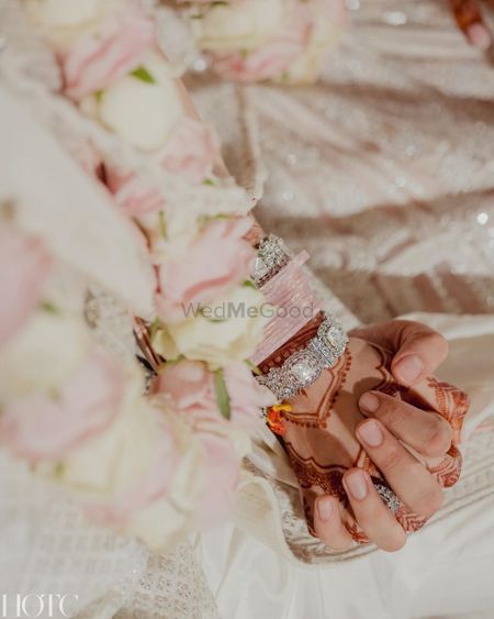 Pretty shot of the couple holding hands with baby pink chooda and minimal mehendi details