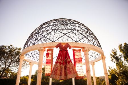 Photo of Red coloured sabyasachi bridal lehenga on hanger over dome