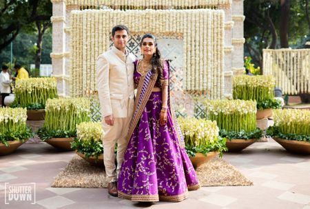 A couple poses in front of a mogra flower decoration for their sangeet ceremony