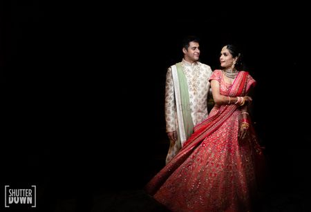 Photo of A bride in red lehenga twirling with her husband