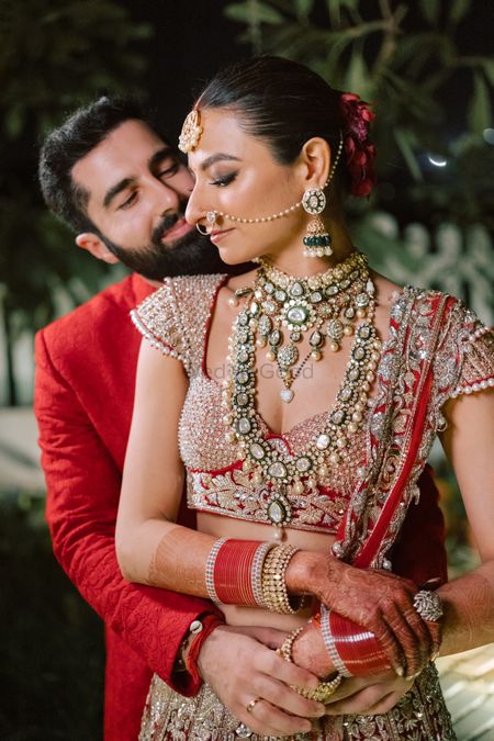 Statement bridal jewellery with a gorgeous red and gold lehenga and the groom in a red sherwani