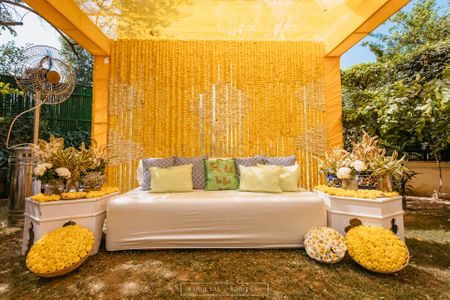 Photo of Beautiful bright bridal seating with marigold and cute bright pillows for the Mehendi day.