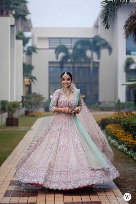 bride twirling in a beautiful pastel lehenga with contrasting dupatta
