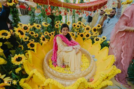 Fun haldi seating idea in a urli surrounded by lotus and sunflower-themed decor