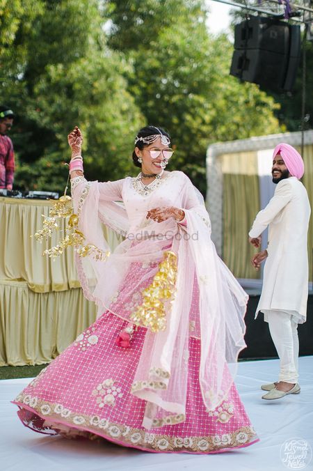 Photo of Bride dancing in light pink minimal bridal lehenga