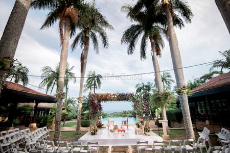 A mandap by the sea with coconut trees. 