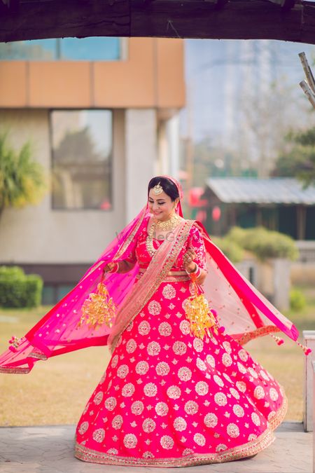 Photo of Bride twirling in a pink lehenga on her wedding day.