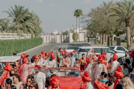 Baraatis entry with the groom in all co-ordinated red safas and a red vintage car