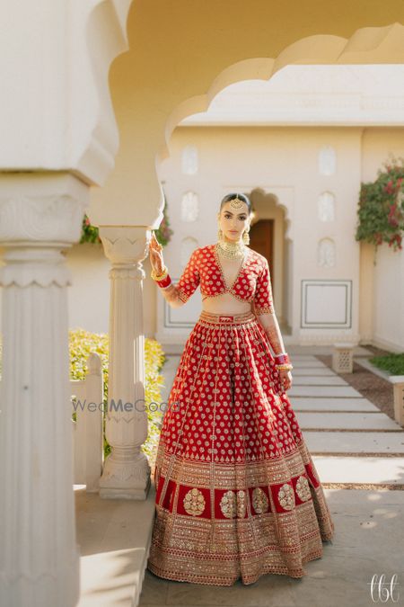 Photo of Bride in an all-red and gold Sabyasachi lehenga with a sleek bun and gold jewellery
