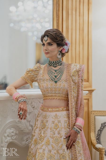 bride in unique lehenga by abu jani and green jewellery 