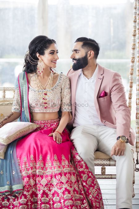 Photo of Bride and groom color-coordinating in pink on their Mehndi.