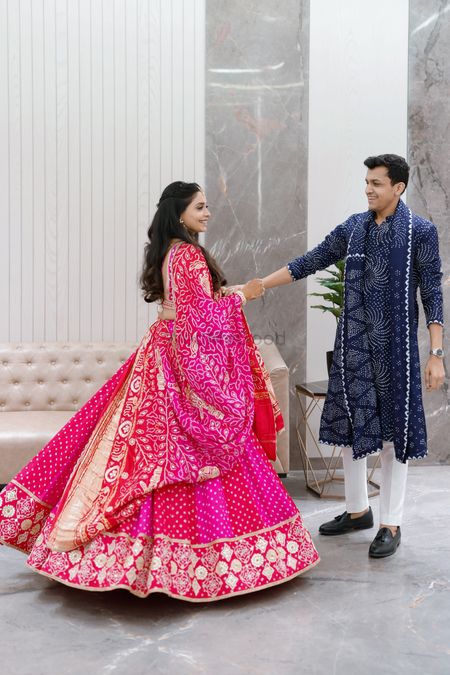 Photo of Coordinated couple in matching bandhani outfits in Fuschia pink and indigo blue
