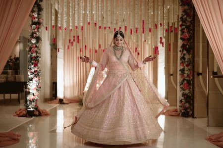 Photo of Bride twirls in a classic pastel pink bridal lehenga.