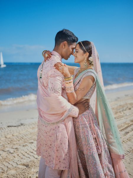 Photo of romantic couple shot by the beach with the bride and groom both wearing light pink