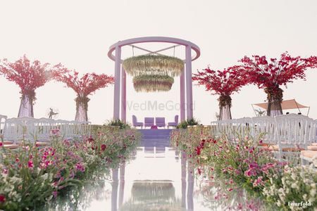 Photo of Gorgeous wedding aisle flanked with floral decor and a mirror-style aisle floor.