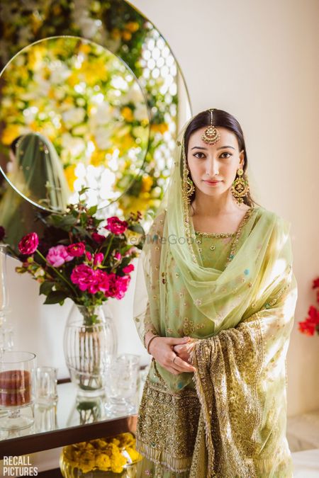 A to-be-bride in a green sharara for her roka ceremony