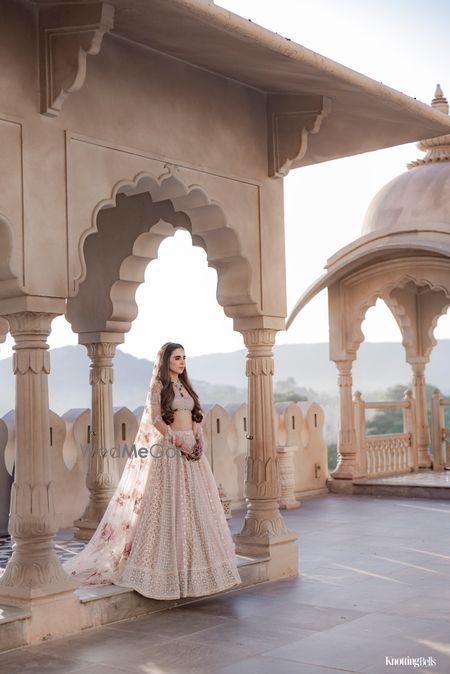 Stunning nude coloured bridal lehenga with a floral dupatta and contrast emerald jewellery