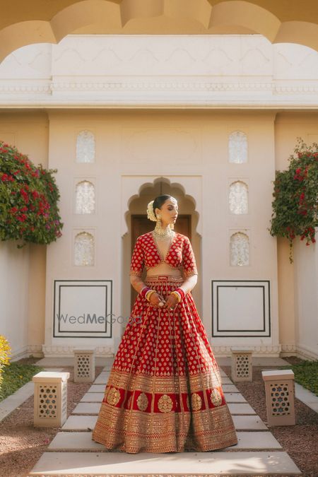 Photo of Timeless bridal portrait in a red and gold Sabyasachi lehenga and a bridal bun with gajra