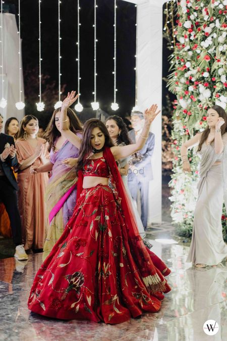 dancing bride in embroidered red lehenga for her sangeet