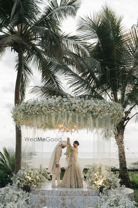 Gorgeous all-white mandap decor with white flowers and couple in matching white outfits