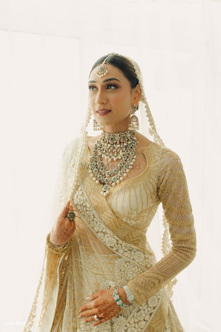 Stunning bridal portrait with layered jewellery and a gold and white lehenga 