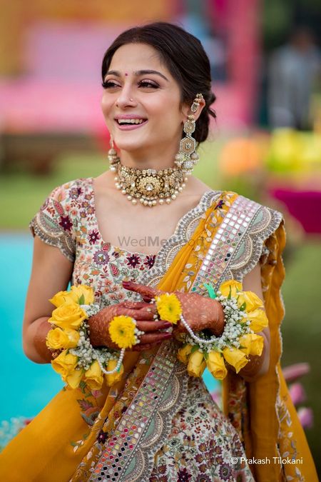 Photo of mehendi bridal look in yellow with floral rose haathphool
