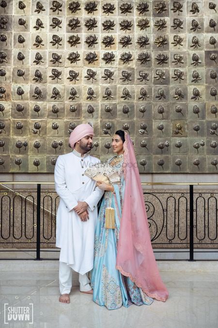 Wedding day couple shot with the groom in an ivory sherwani and the bride in a pastel lehega. 