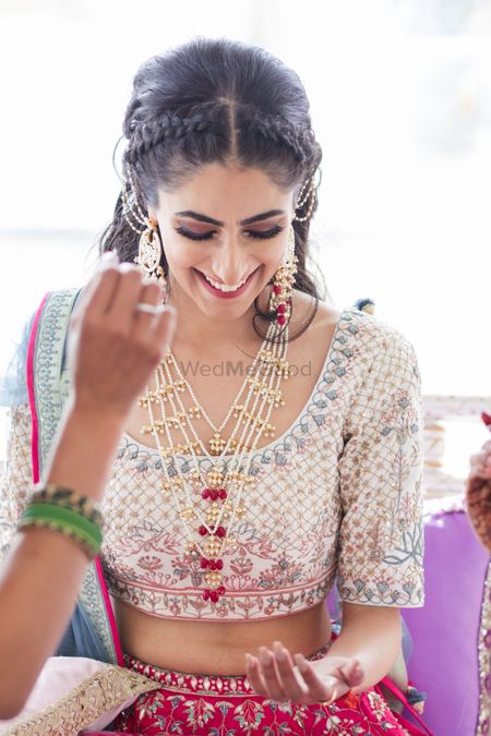 A candid shot of a bride smiling at her mehndi ceremony.