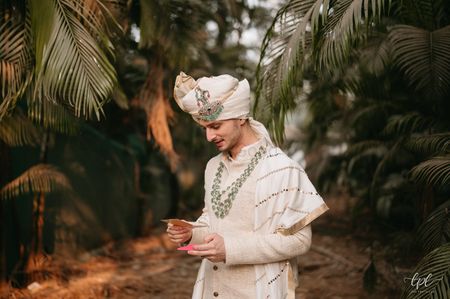 white groom sherwani with emerald jewellery 