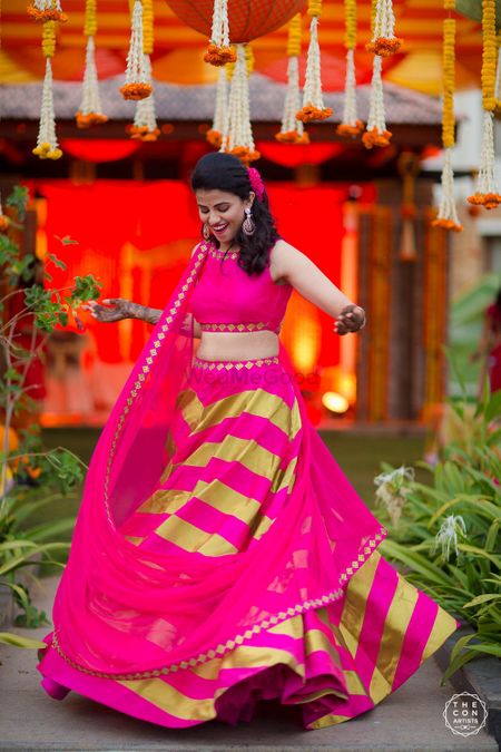 Bride twirling on mehendi in bright pink and lime green lehenga 