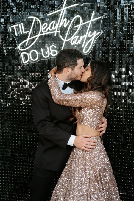 Bride and groom kissing against a neon signage 