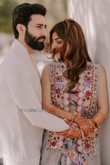 Photo of Lovely couple shot with a bride in a gorgeous floral jacket and the groom in an all-white ensemble.