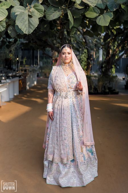 Bride in a pastel lehenga with all over embroidery