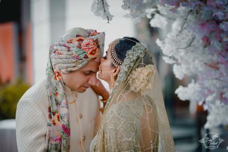 Bride kissing groom with floral safa 