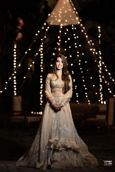 A bride in a tasseled gold lehenga for her sangeet