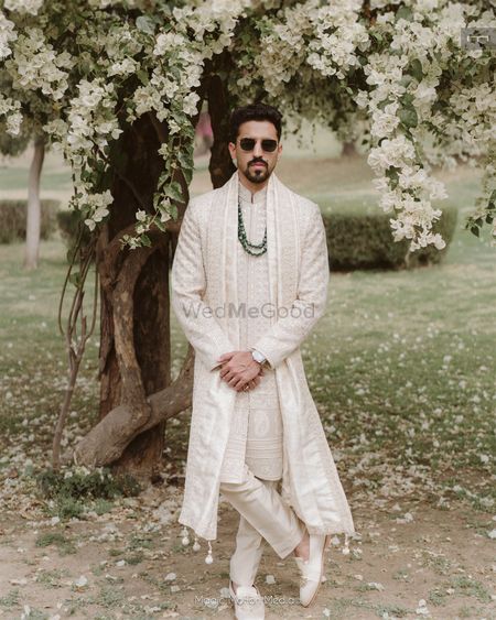 Photo of All white sherwani with vintage sunglasses groom portrait