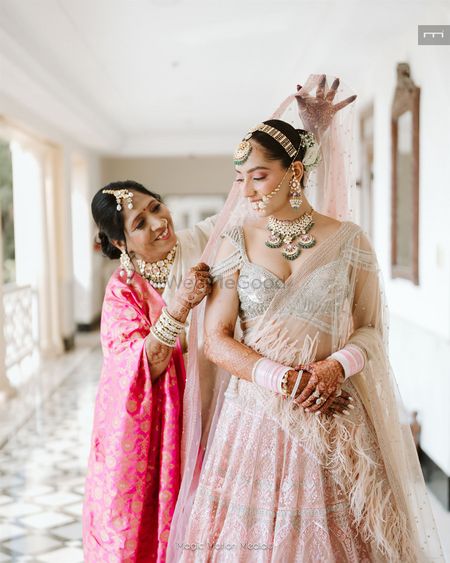 Photo of Mom of the bride placing the dupatta on the bride's head on her wedding day