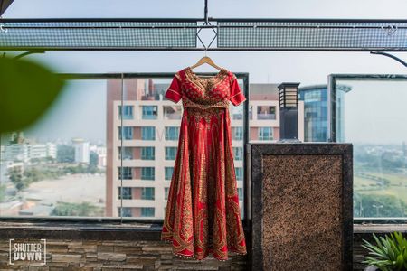 Red bridal lehenga on hanger with blouse