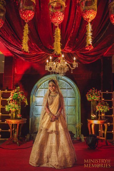 Bride posing in gold lehenga with red decor