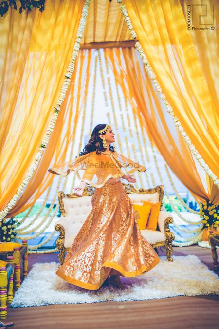 Photo of Bride dancing in mustard mehendi benarasi lehenga