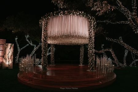 Photo of Stunning stage decor in mandap style with hanging florals on a wooden stage