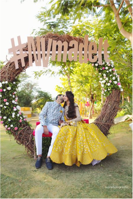Couple kissing in front of mehendi photobooth