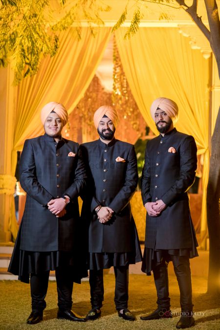 groomsmen in black sherwani with peach peach safa