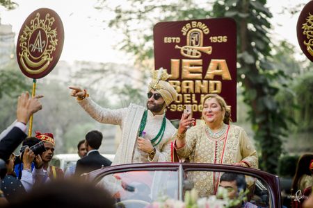 Groom in a vintage car for his baraat with his mother by his side