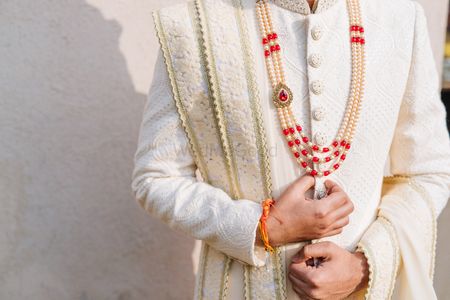 Photo of Groom in exquisite jewellery and embroidered cream sherwani.