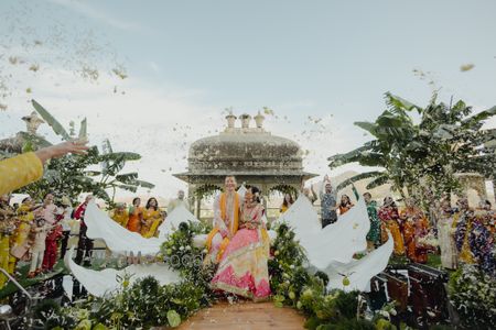 Candid shot of the bride and groom on the floating stage under a flower shower